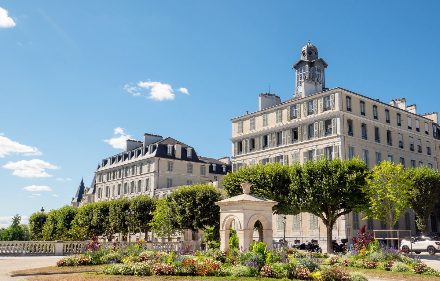 Immeubles anciens et jardin fleuri du boulevard des Pyrénées à Pau sous un ciel bleu